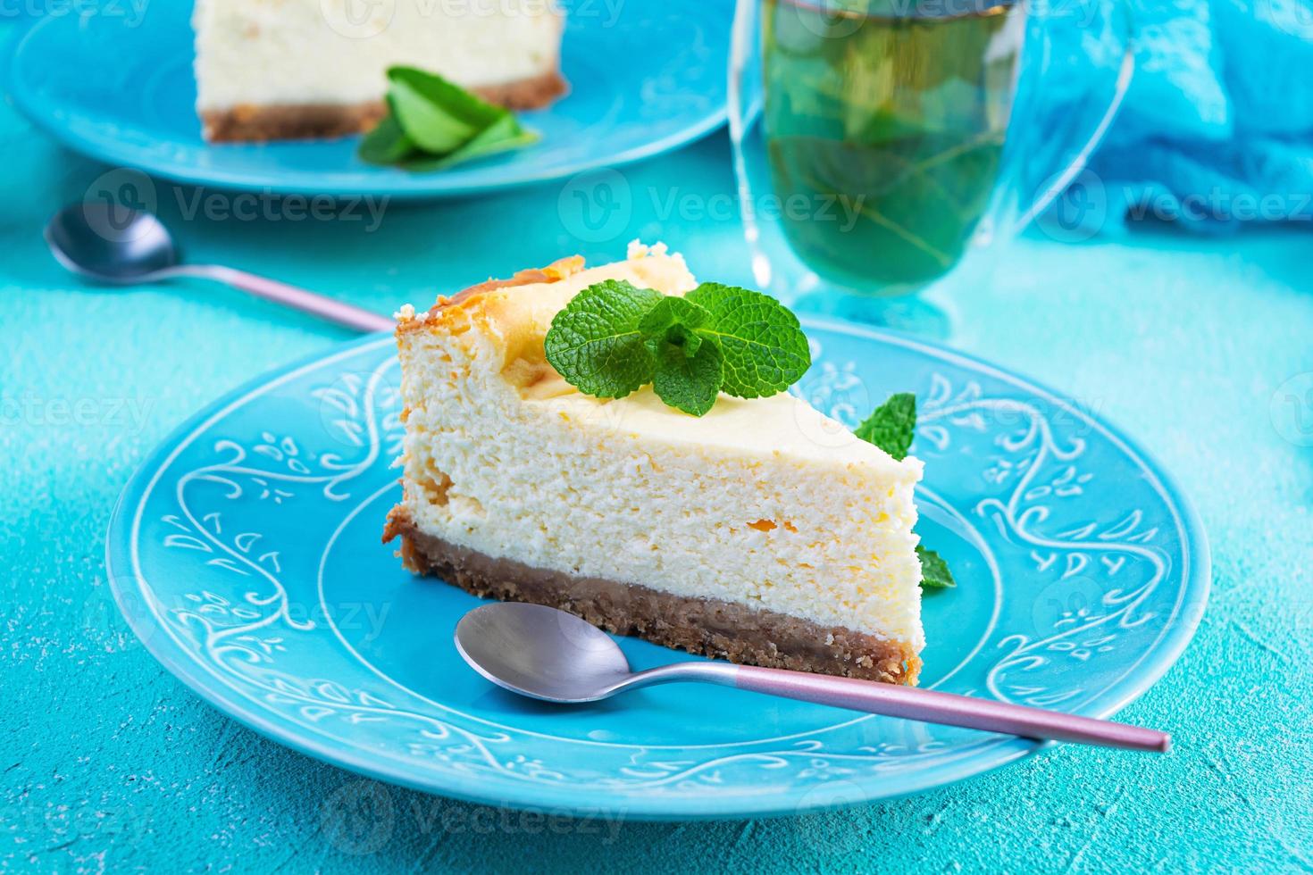 tarta de queso en rodajas. delicioso pastel de queso dulce con té de menta sobre fondo azul foto