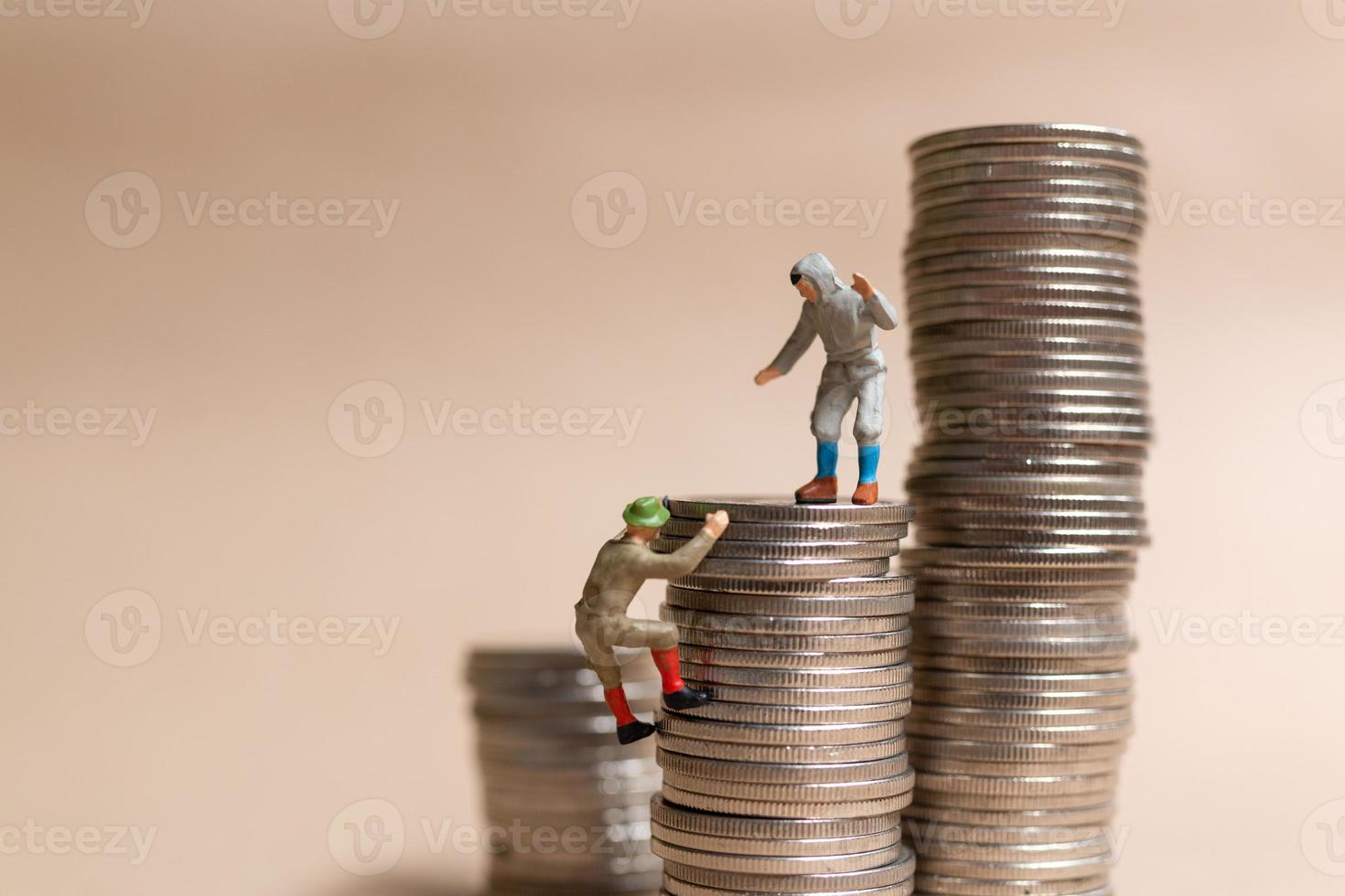 Miniature people Mountain climber ascending the coin stack photo