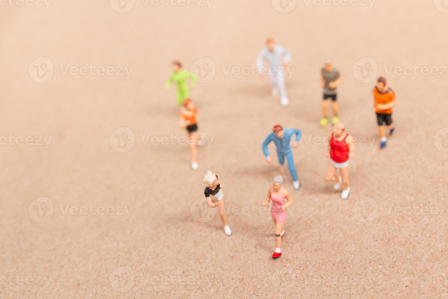 Miniature People exercising while running in a group on the beach photo