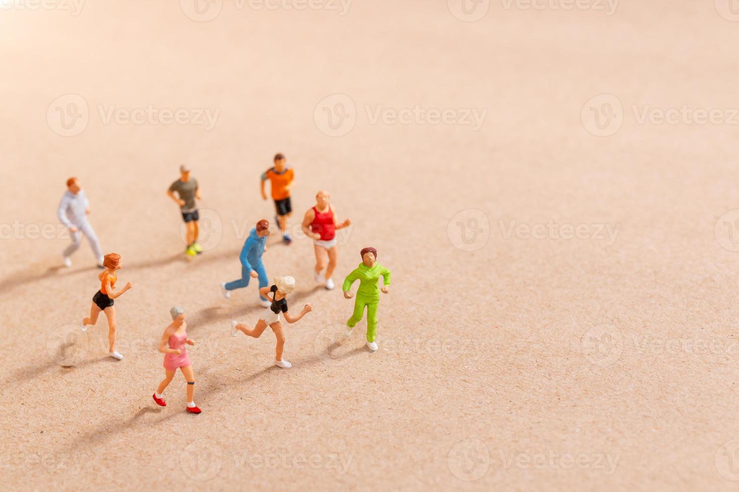 Miniature People exercising while running in a group on the beach photo