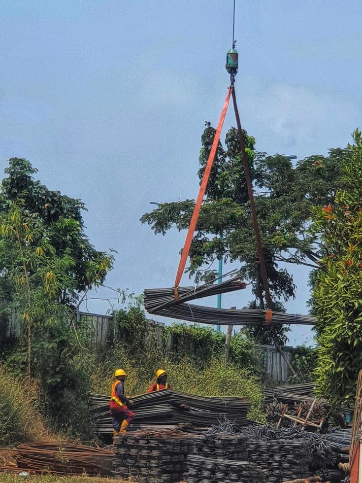 Two construction workers are mobilizing pieces of structural steel. This process is carried out with the help of cranes and slings. photo