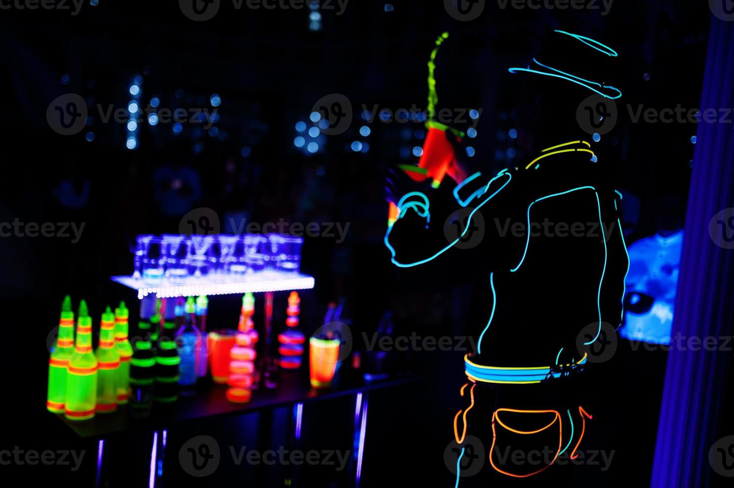 Professional barman and led light show. Silhouette of modern bartender shaking drink at night cocktail bar. photo