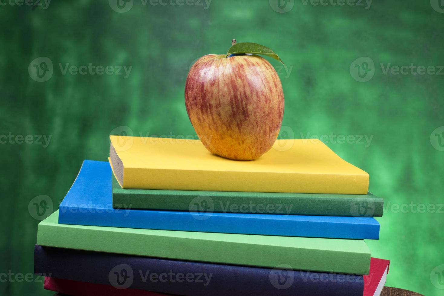 fruta de manzana encima de una pila de libros, en la parte posterior de las clases escolares. foto