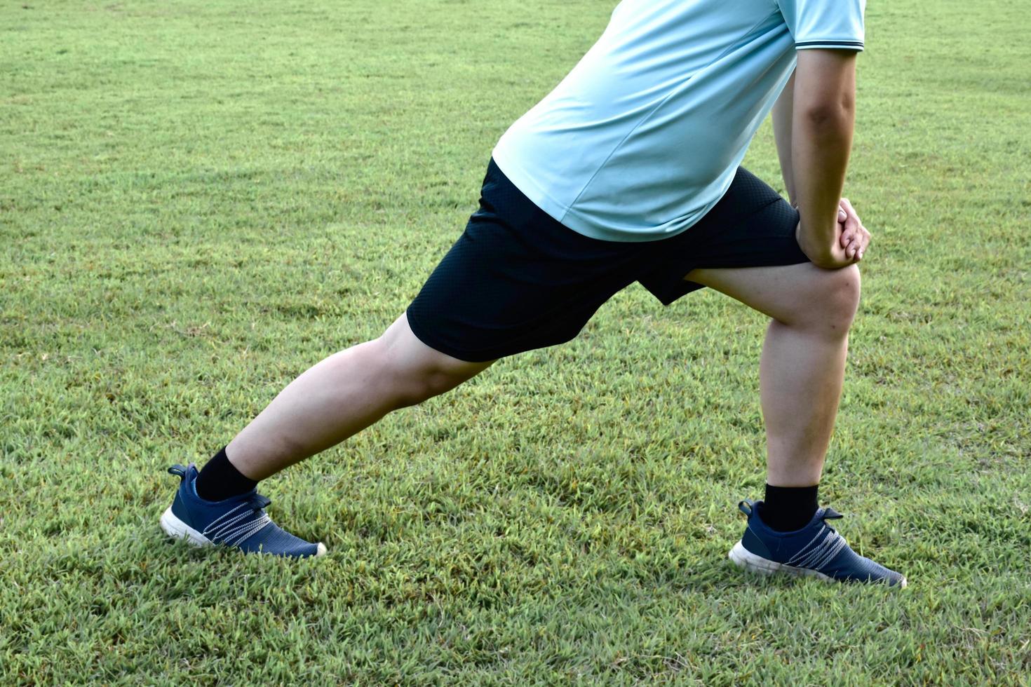 Middle aged asian man runner stretching on the grass lawn relaxing after and before running in the park. Healthy lifestyle with outdoor exercising concept photo