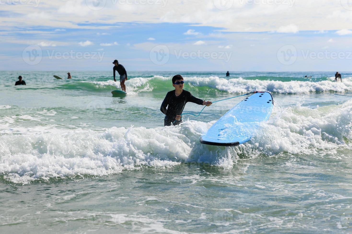 A young boy eagerly wearing a bathing suit and goggles is practicing surfing. photo