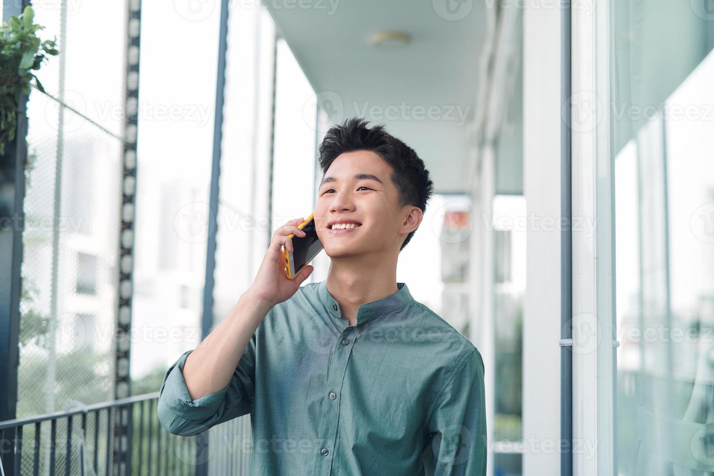 hombre guapo que tiene una conversación seria en el teléfono celular afuera en el balcón foto