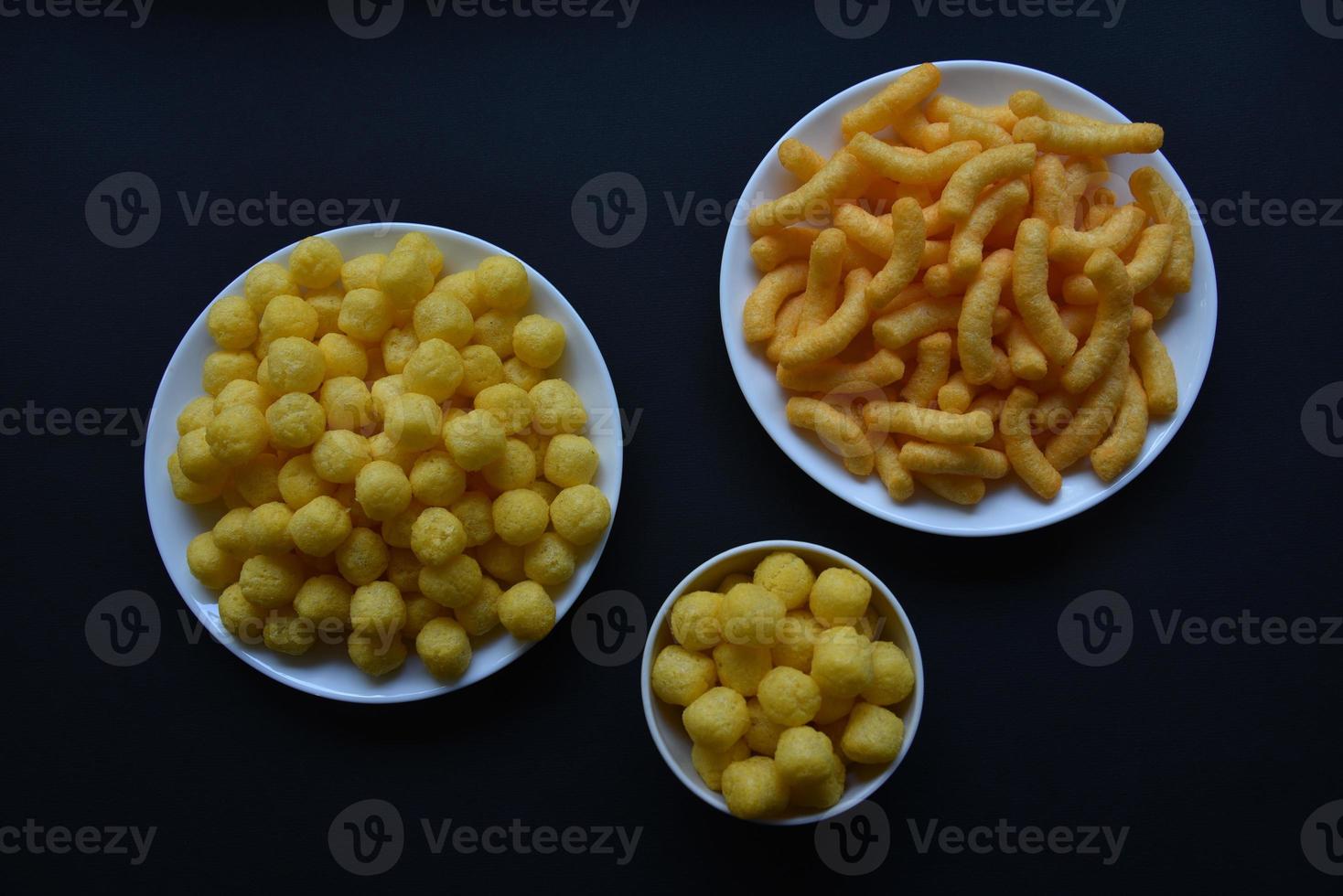 Corn salted and peppered chips on a white plate. Delicious breakfast of corn chips on a black background. photo