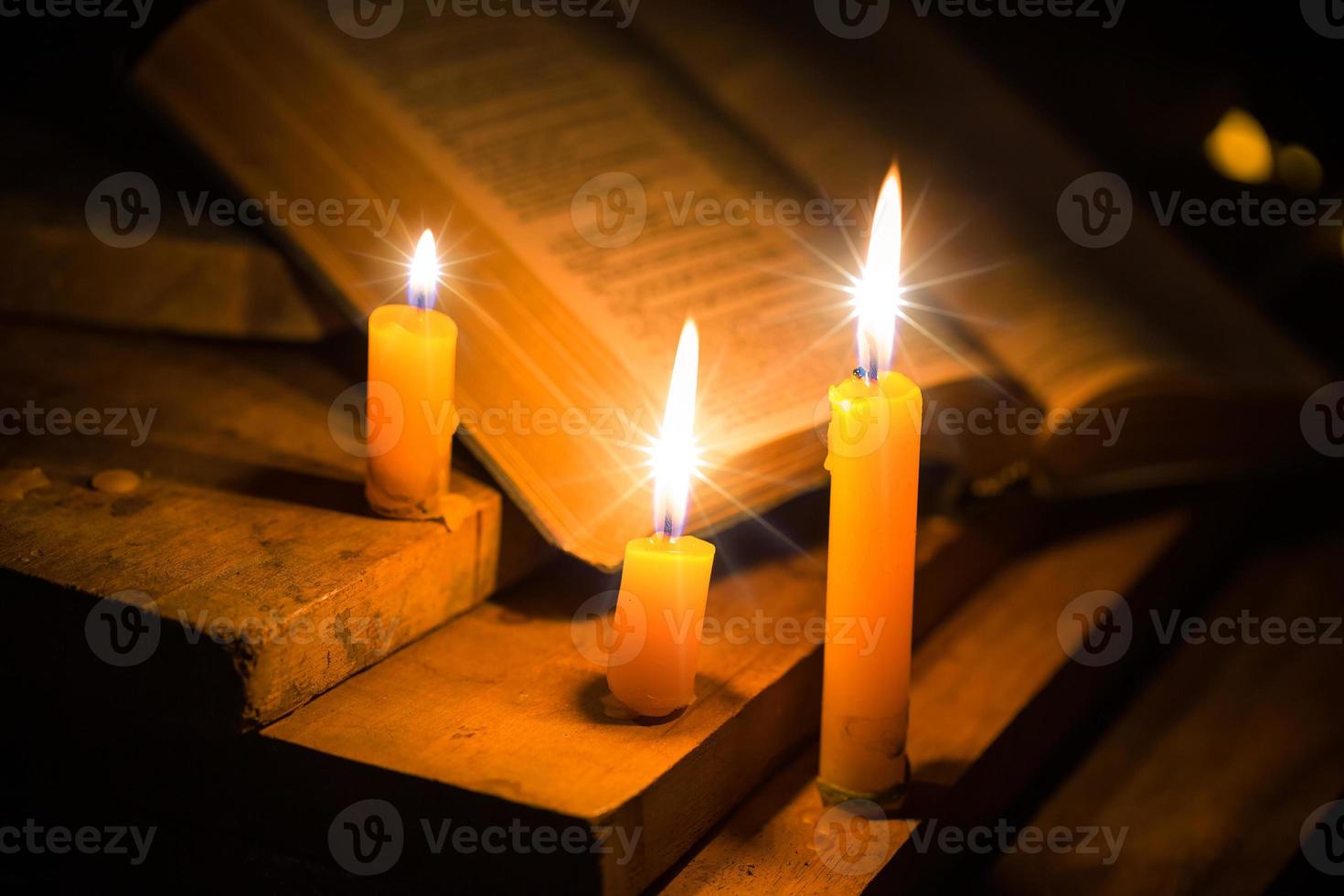 Light candle with holy bible and cross or crucifix on old wooden background in church.Candlelight and open book on vintage wood table christianity study and reading in home.Concept of christ religion photo