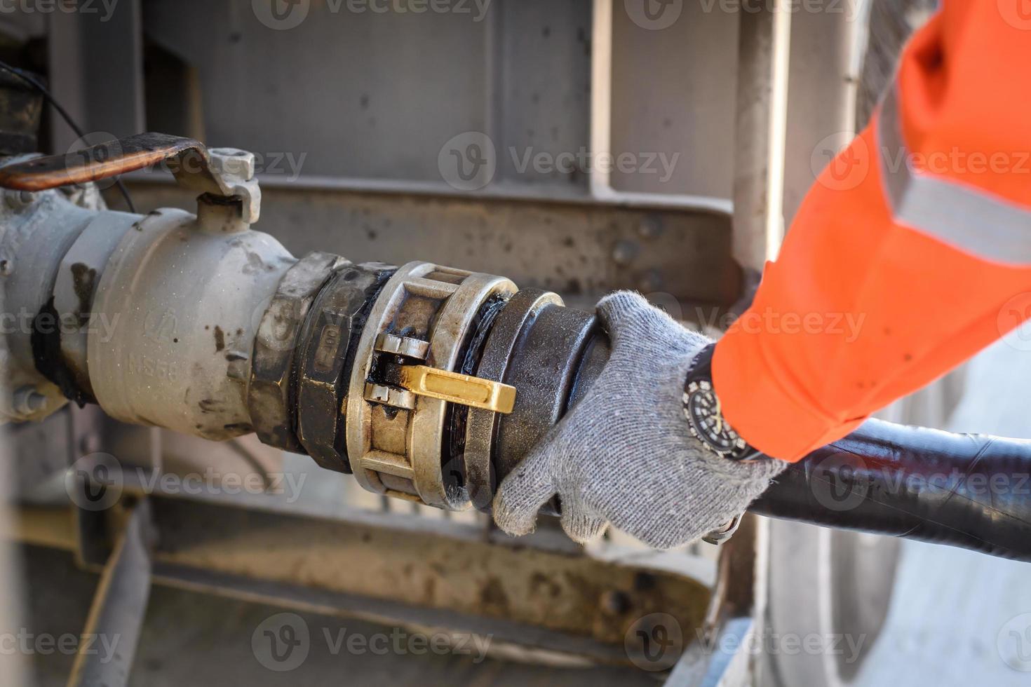 A man works in an oil field and is using oil pipes to refuel. photo