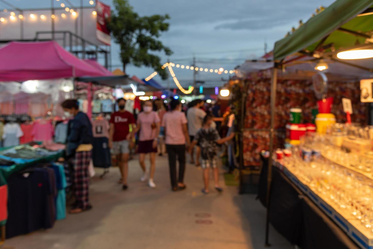 imagen borrosa de la gente del festival del mercado nocturno caminando por la carretera con un ligero bokeh de fondo. foto