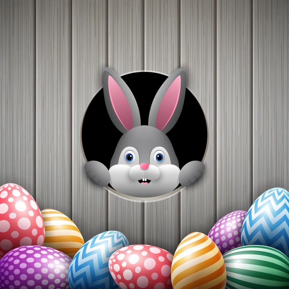 Cute Easter bunny peeking out of a hole with colorful eggs vector