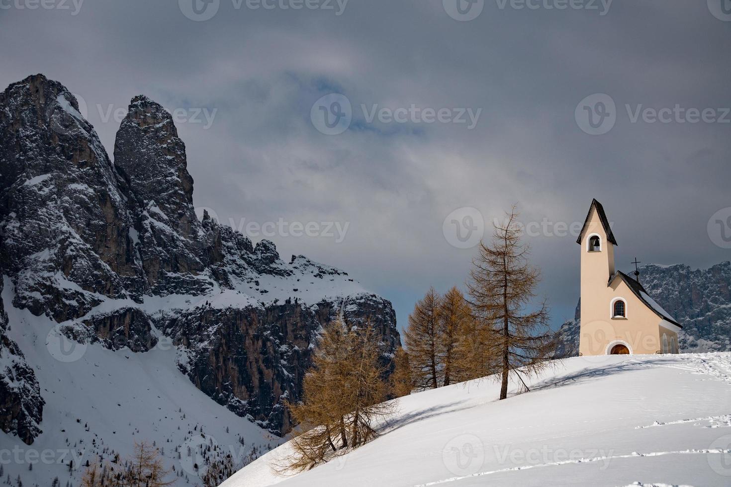 vista de la iglesia de dolomitas en tiempo de nieve de invierno foto
