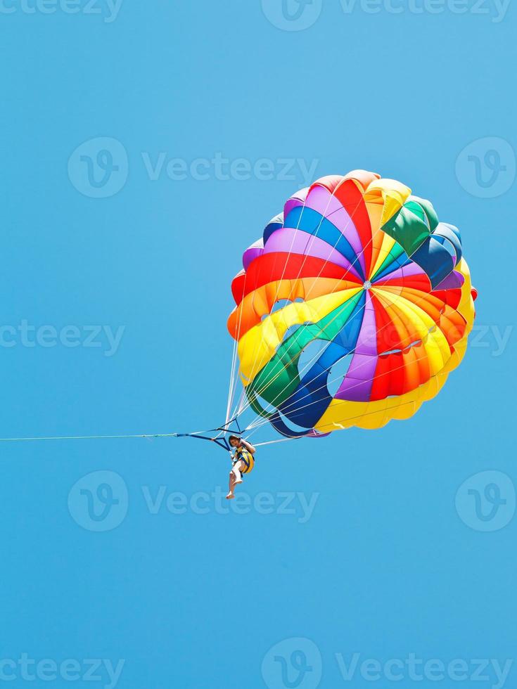 chica parakiting en paracaídas en el cielo azul foto
