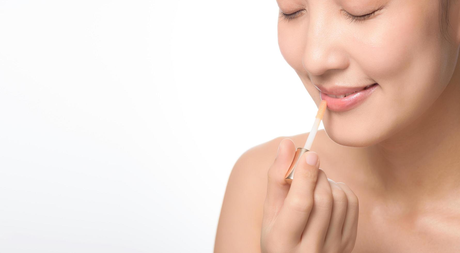 Beautiful portrait young asian woman looking mirror applying makeup lipstick at room. photo