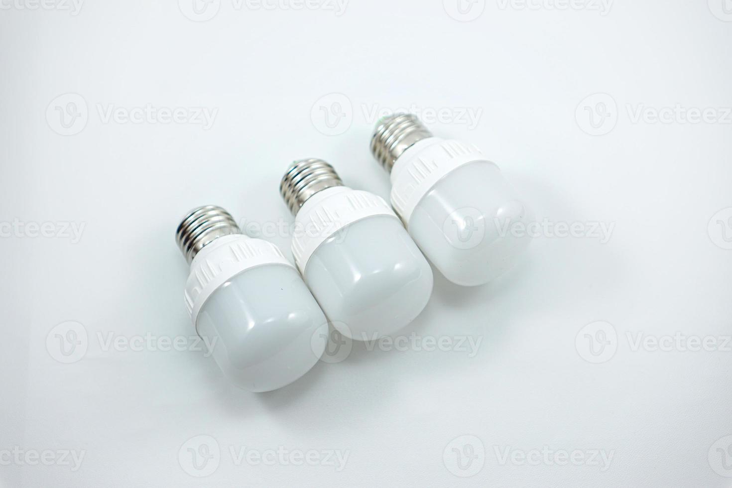 concept of three small white energy-saving light bulbs isolated on a white photo