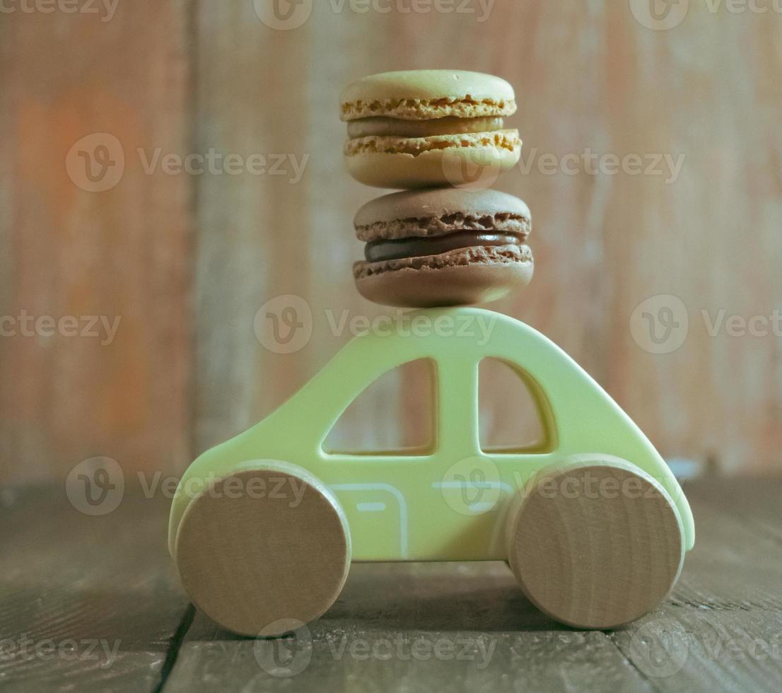 macarons dulces en coche de juguete de madera foto