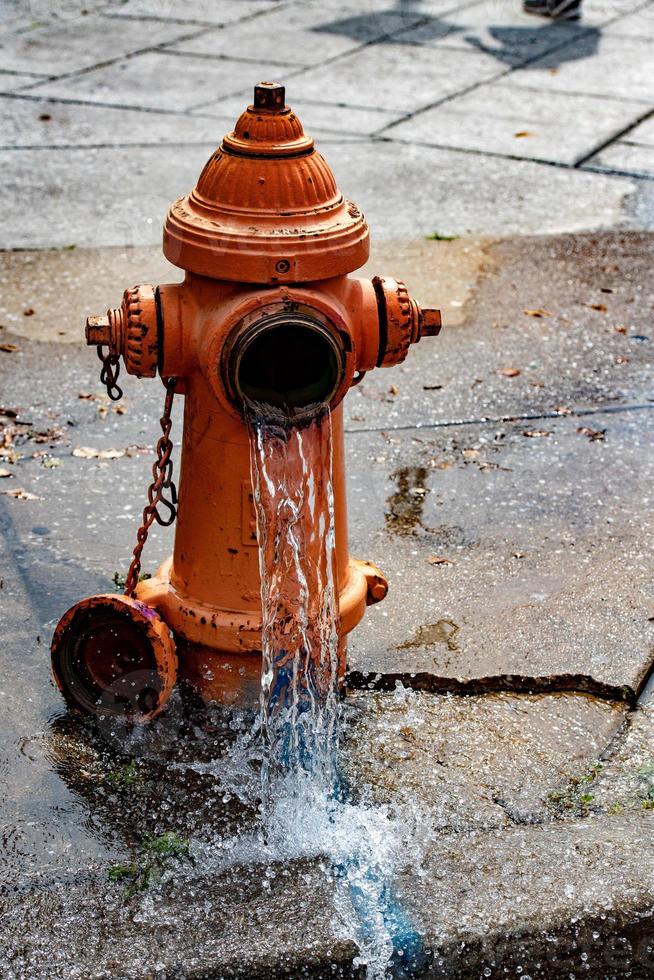 Street orange hydrant spreading water on the street photo