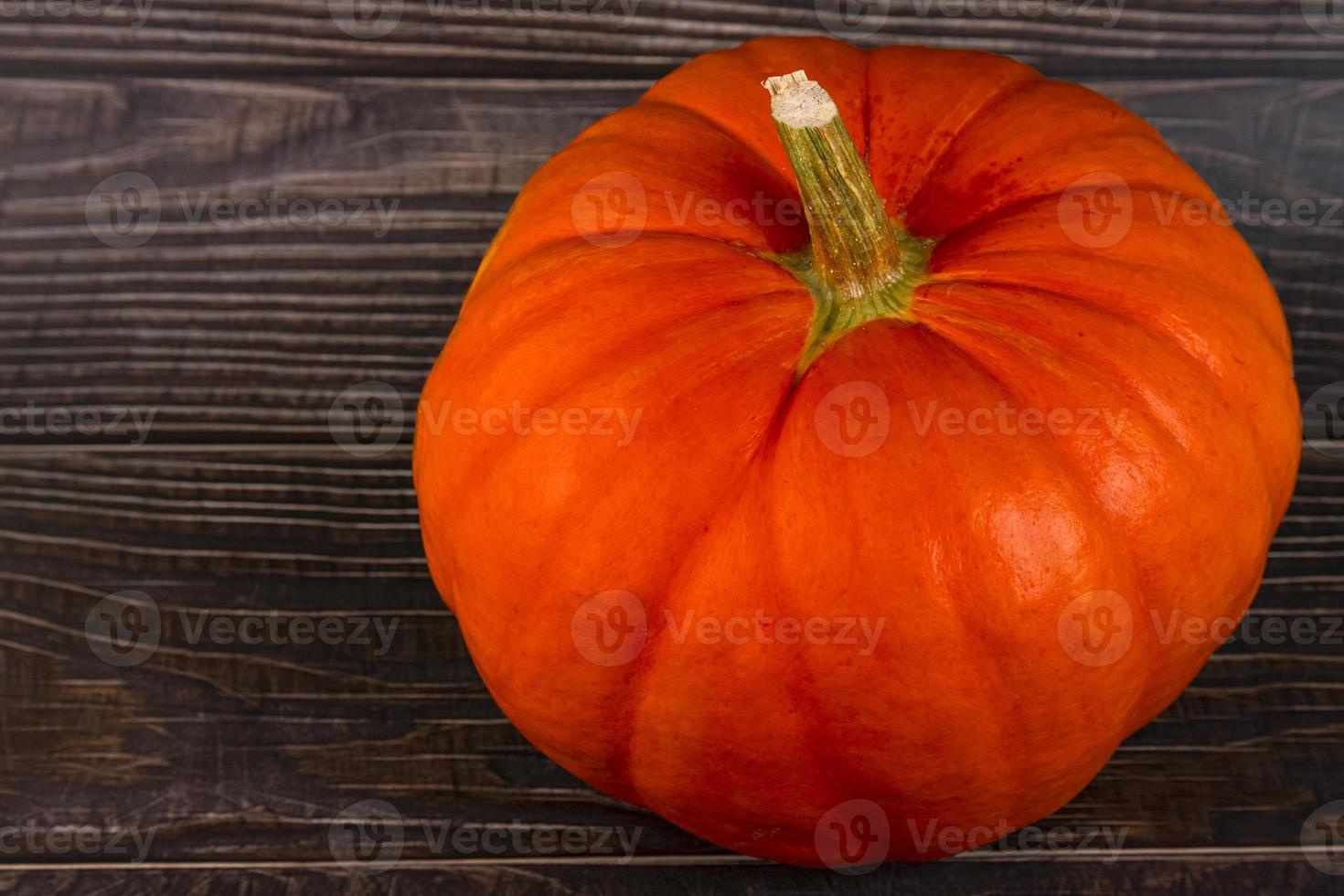 Orange pumpkin with a stem, close-up on a plank, wooden background. Autumn background. Copy space. photo