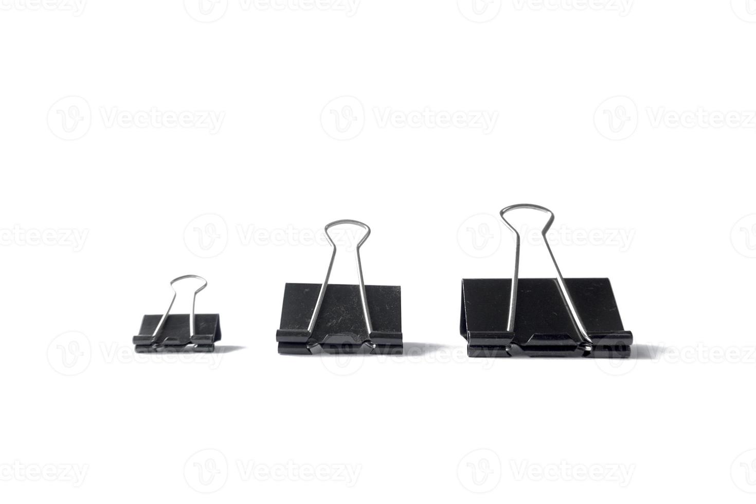 Three black binder clips of various sizes used to staple documents against photo