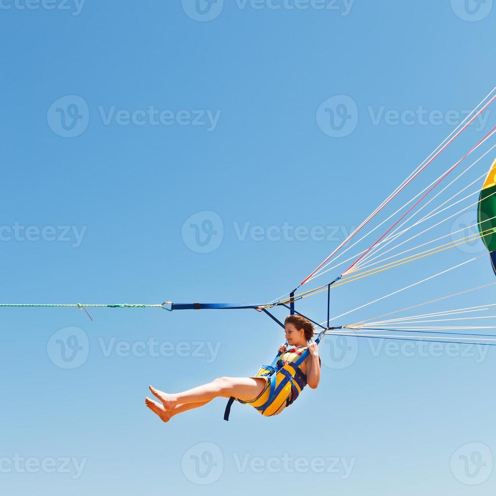 chica parapente en paracaídas en el cielo azul foto