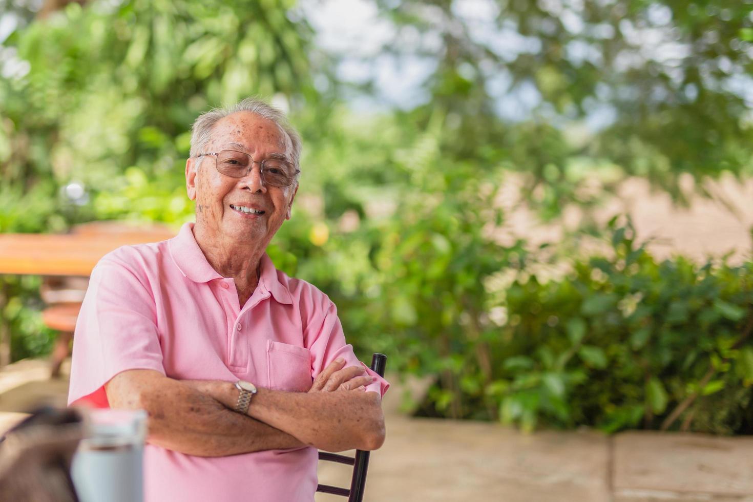 Portrait asian elderly man 83 years old with toothy smile sitting outdoor in the garden. photo