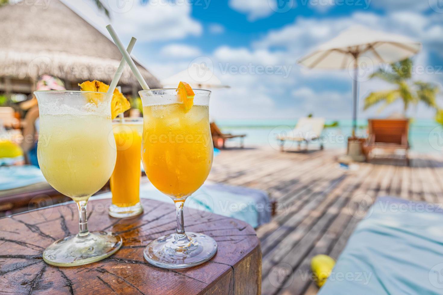 copas de cóctel en la piscina, al lado de la playa. piscina tropical soleada con cielo azul brillante. libertad recreativa, concepto despreocupado, vacaciones de viaje. bebidas frías con piscina tropical borrosa. exótico foto