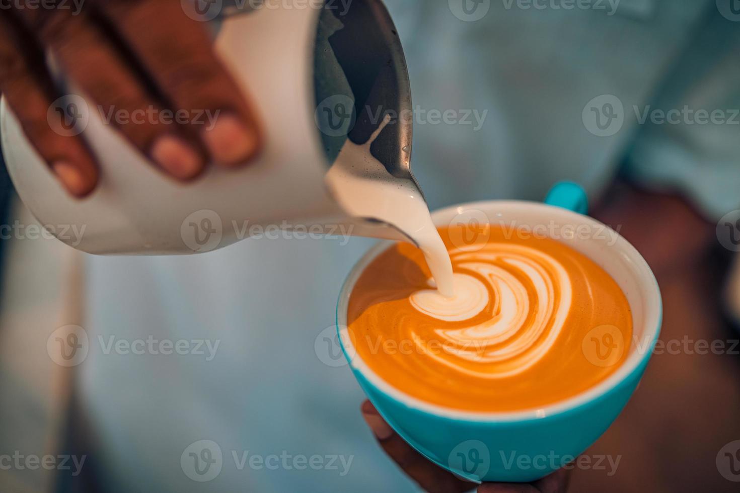 primer plano abstracto de la cafetería, taza de café latte art. barista haciendo una taza de café latte art. tono vintage de algunas personas vierten leche para hacer café con leche foto