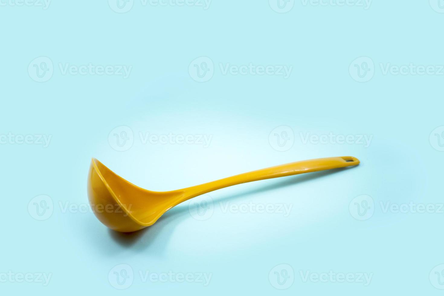 cucharón amarillo usado para sacar sopa aislado en una turquesa foto