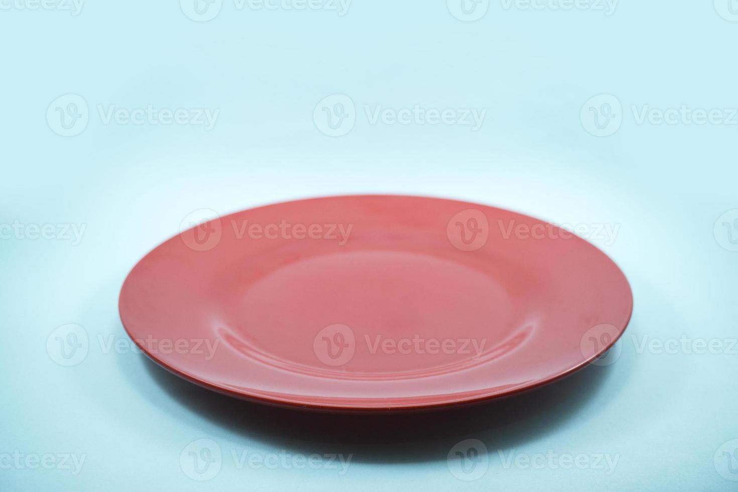 empty plastic red plate isolated on turquoise background. photo