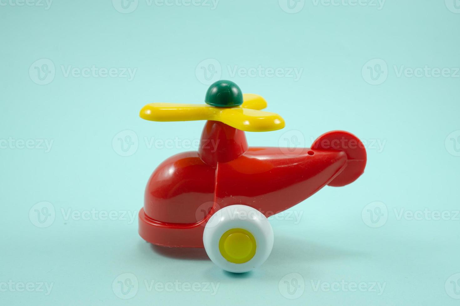 Yellow paint plastic toy airplane with red propeller isolated on turquoise photo
