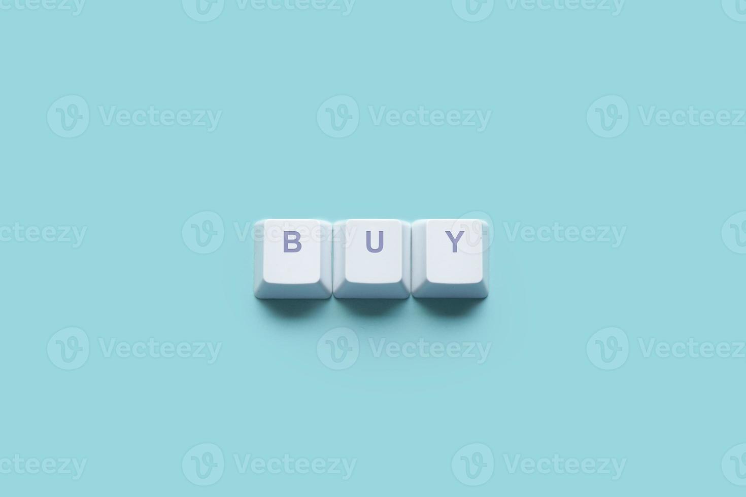 Word BUY written on computer keyboard keys isolated on a turquoise photo