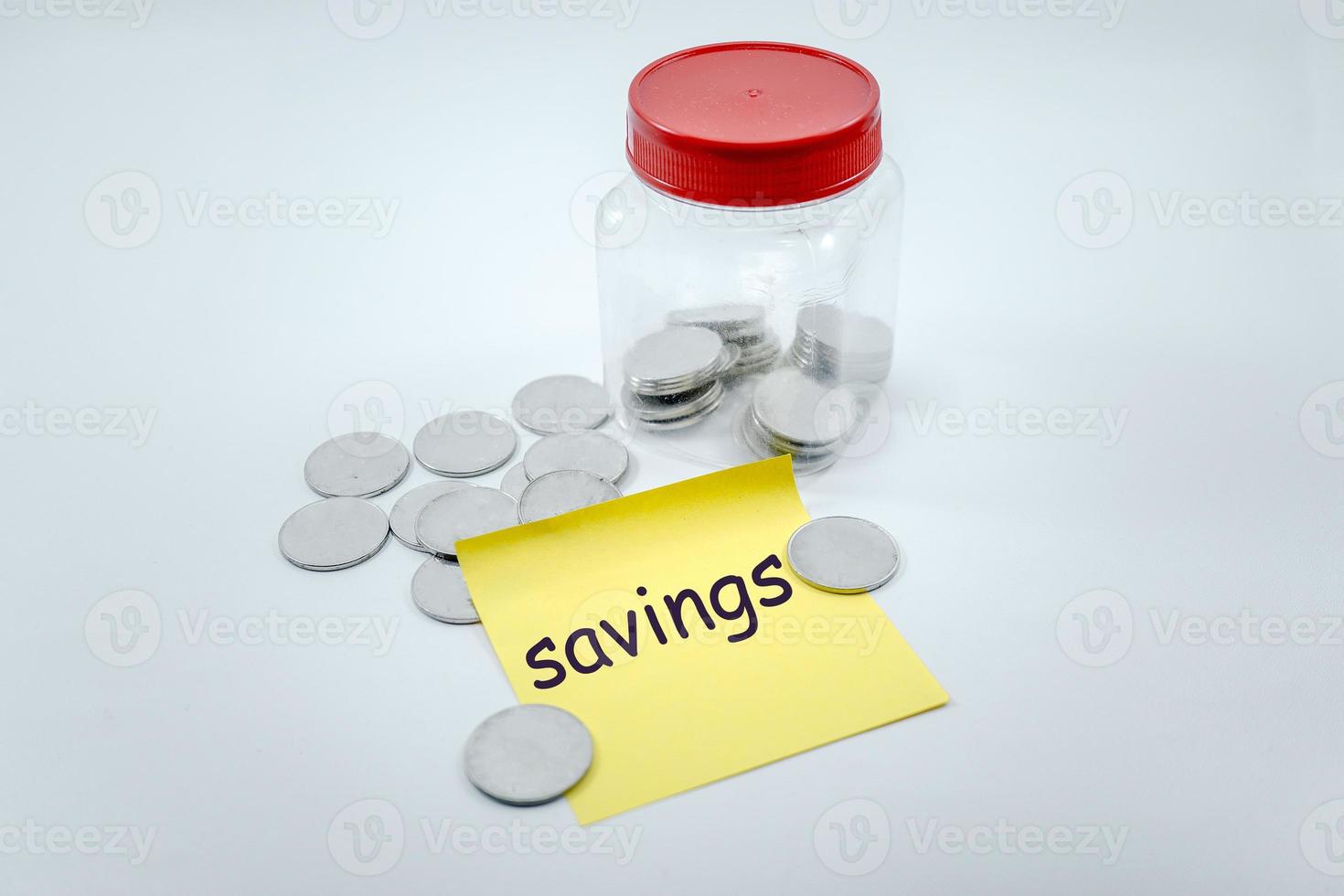 savings, scattered coins and in plastic jar with sticky note that says savings photo