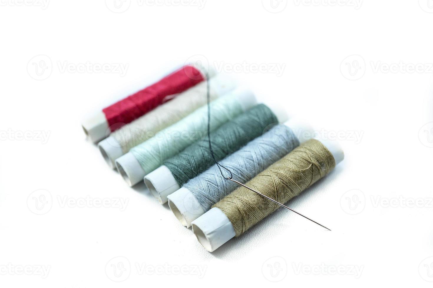 Rows of sewing threads of various colors and sewing needles isolated on white photo