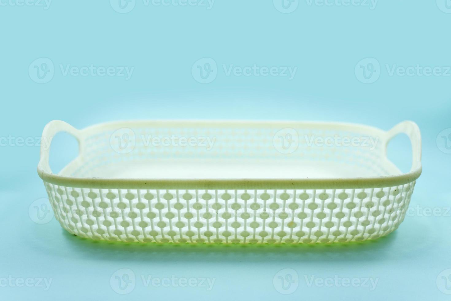 white plastic basket with woven pattern isolated on a turquoise photo