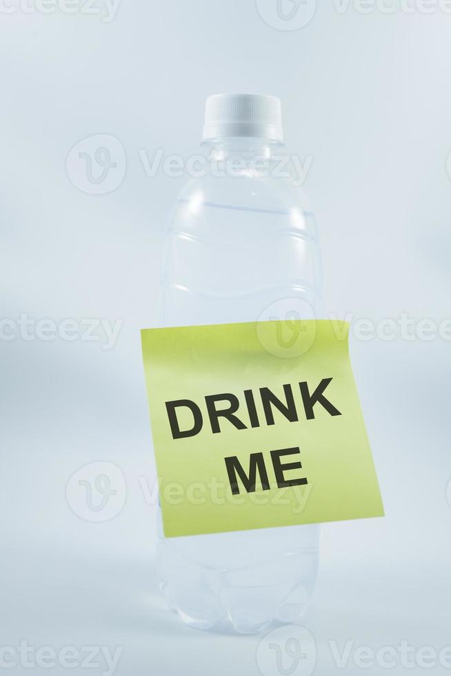 bottle plastic with a sticky note that says drink me. isolated on white. photo