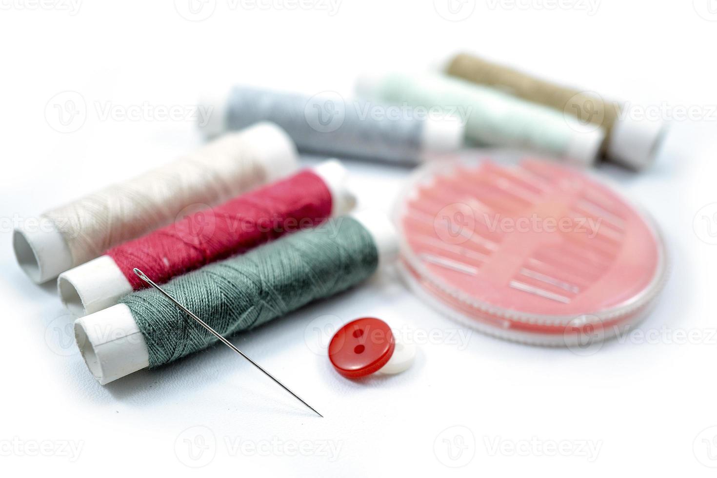 Rows of sewing threads of various colors, sewing needles and shirt buttons photo