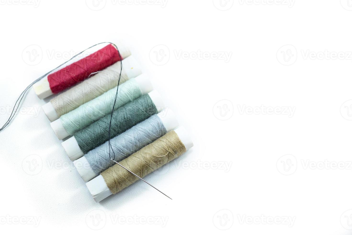 Rows of sewing threads of various colors and sewing needles isolated on white photo
