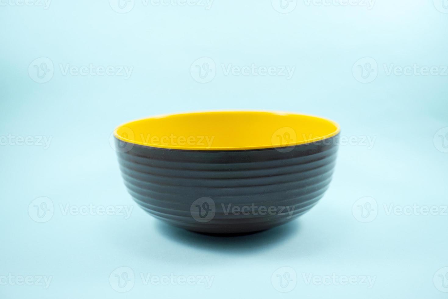 empty brown plastic bowl with yellow inside isolated on turquoise photo