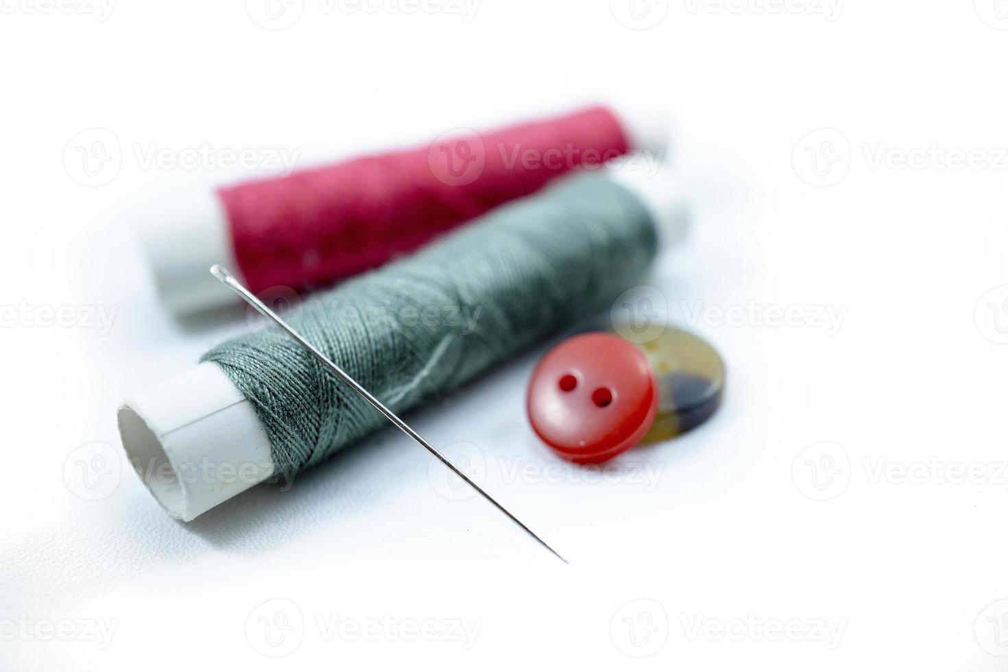 Rows of sewing threads of various colors, sewing needles and shirt buttons photo