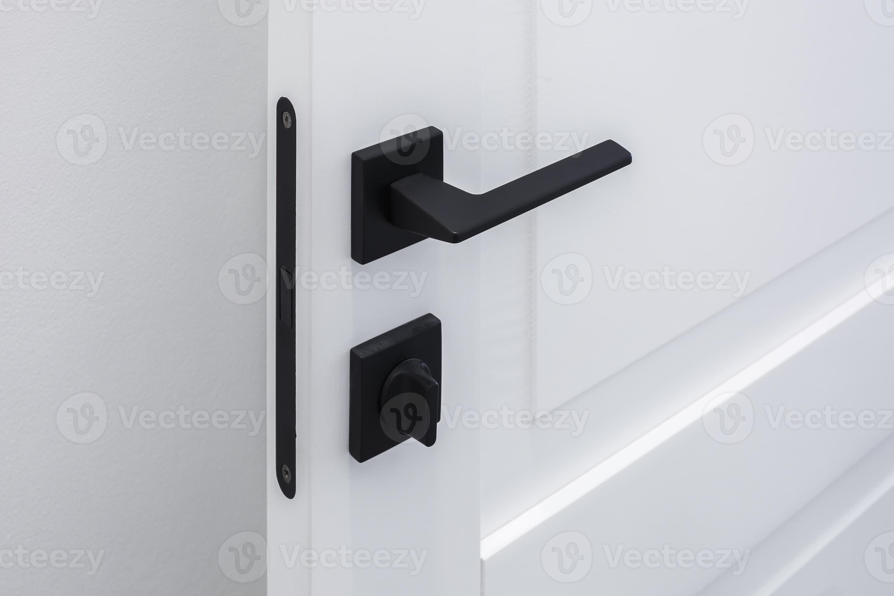 Modern black door handle on white wooden door in interior. Knob closeup elements. Door handle