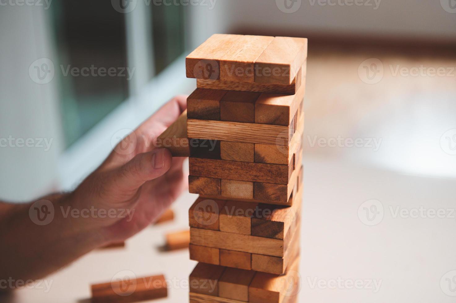 Wooden blocks toy puzzle with human hand on table at home background. Entertainment and business concept. photo