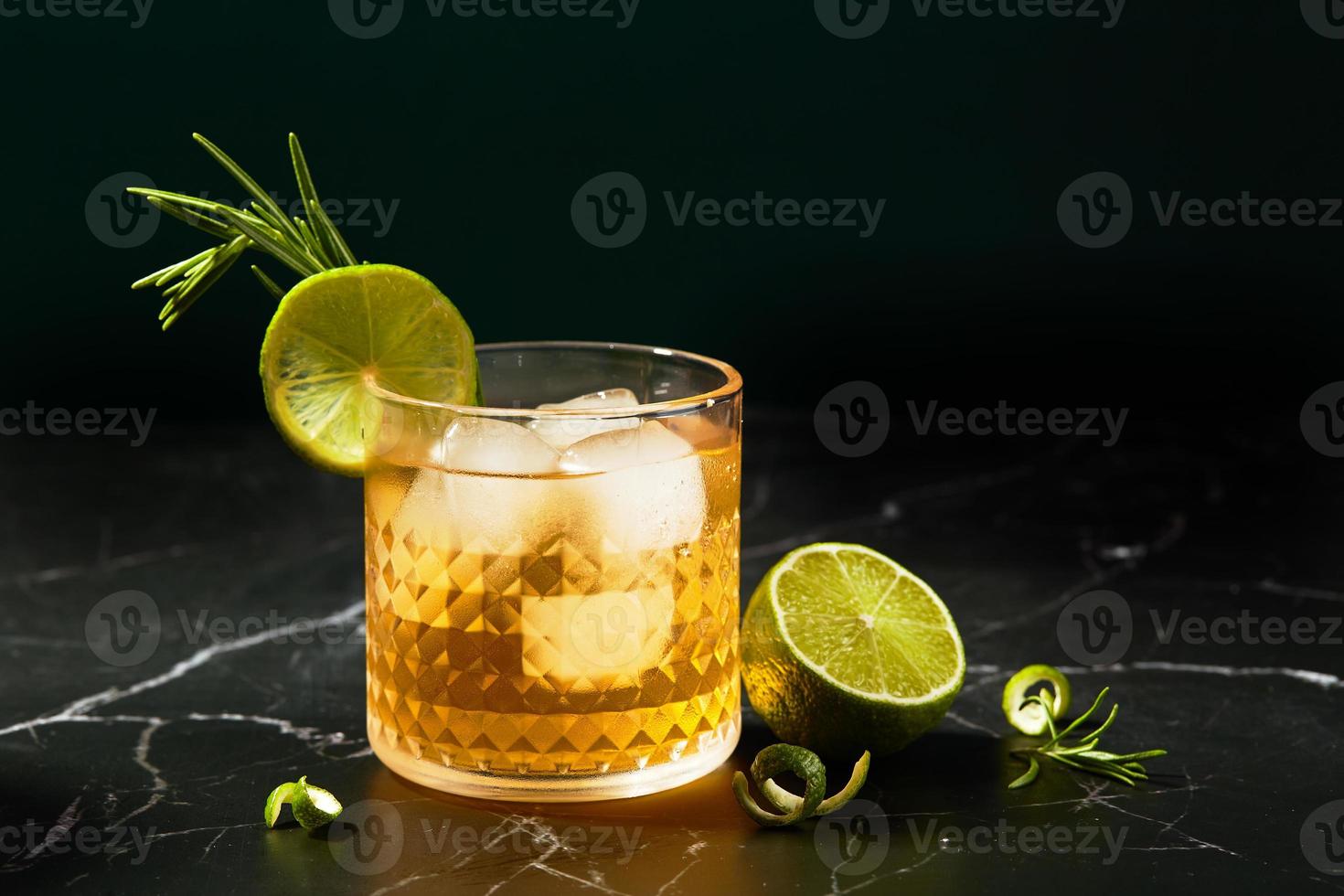 Alcoholic or non-alcoholic cocktail with lime and rosemary on a dark marble table photo