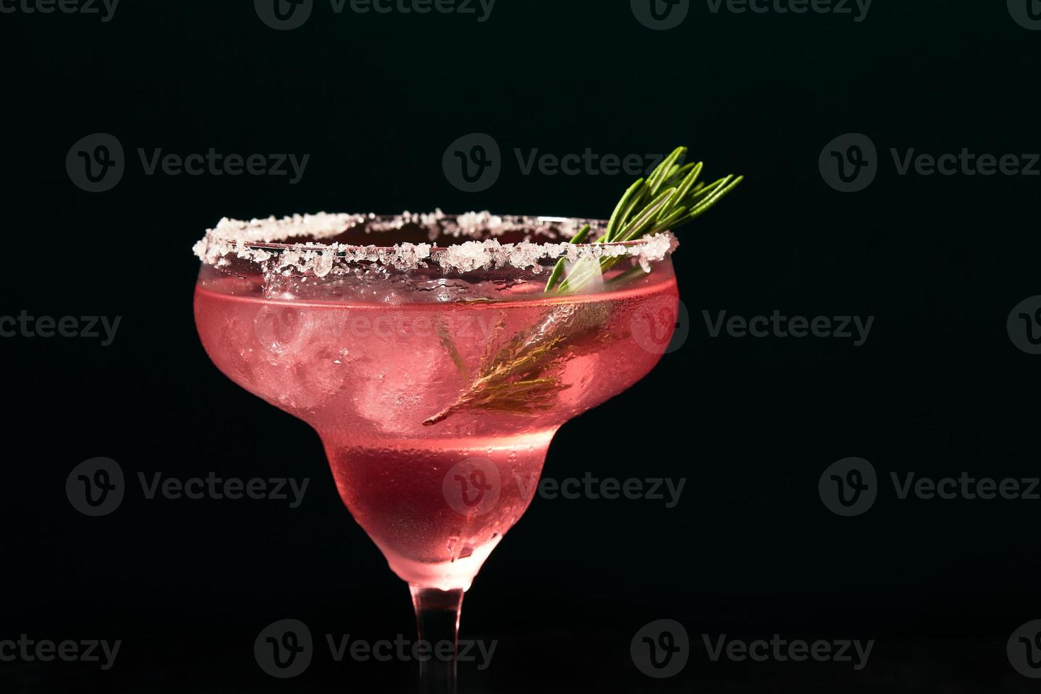 Alcoholic or non-alcoholic rosemary cocktail such as margarita, cosmopolitan or similar on a dark marble table photo