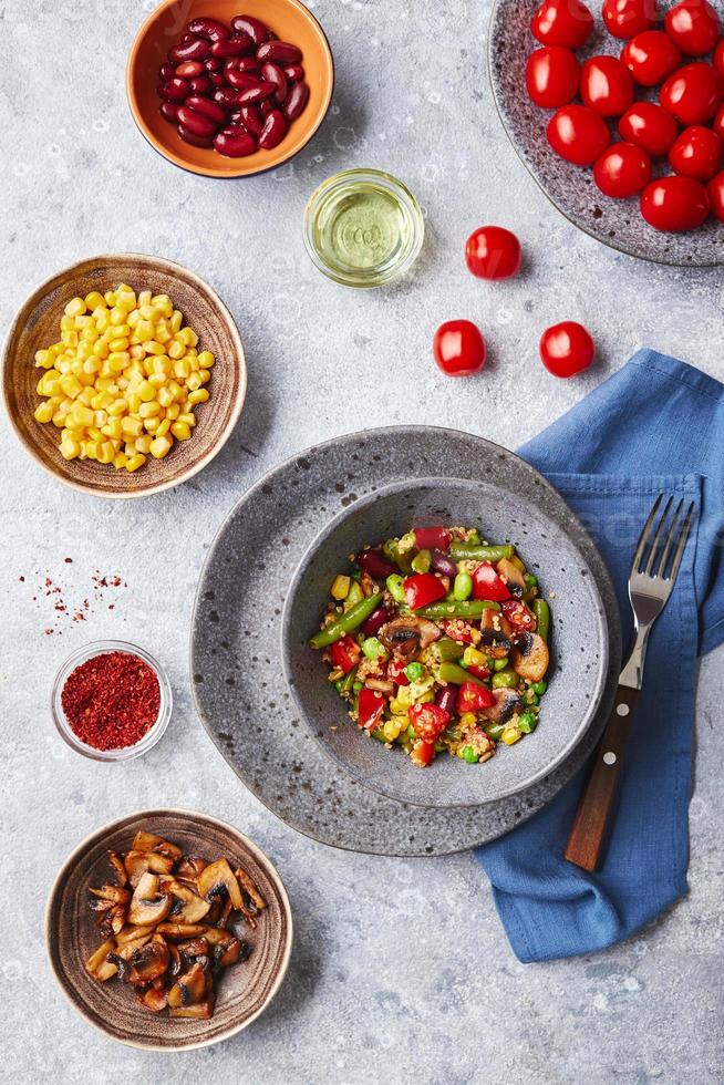 quinua con judías verdes, tomates, champiñones fritos, maíz, pimientos rojos, guisantes y soja. mezcla saludable de vegetales foto