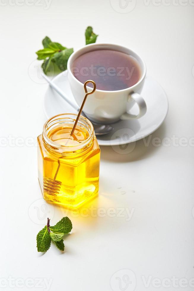 Black tea in white cup with mint leaves and honey. Calming and revitalizing tea, anti-stress and relaxation photo