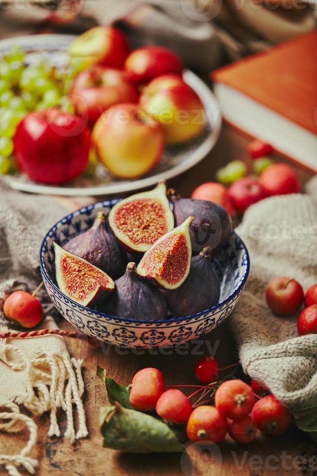 Dish with figs, apples and grapes with warm cozy knitwear, autumn leaves and apples. photo