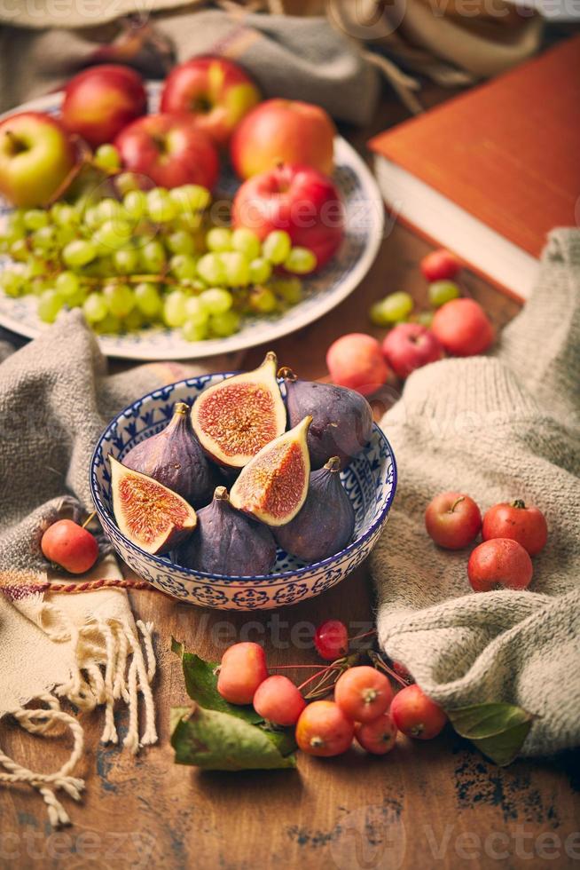 Dish with figs, apples and grapes with warm cozy knitwear, autumn leaves and apples. photo