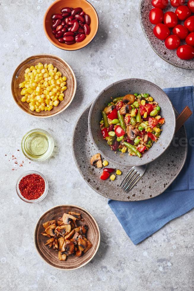 quinua con judías verdes, tomates, champiñones fritos, maíz, pimientos rojos, guisantes y soja. mezcla saludable de vegetales foto