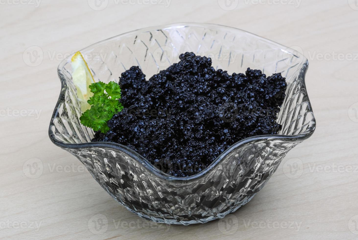 Black caviar in a bowl on wooden background photo