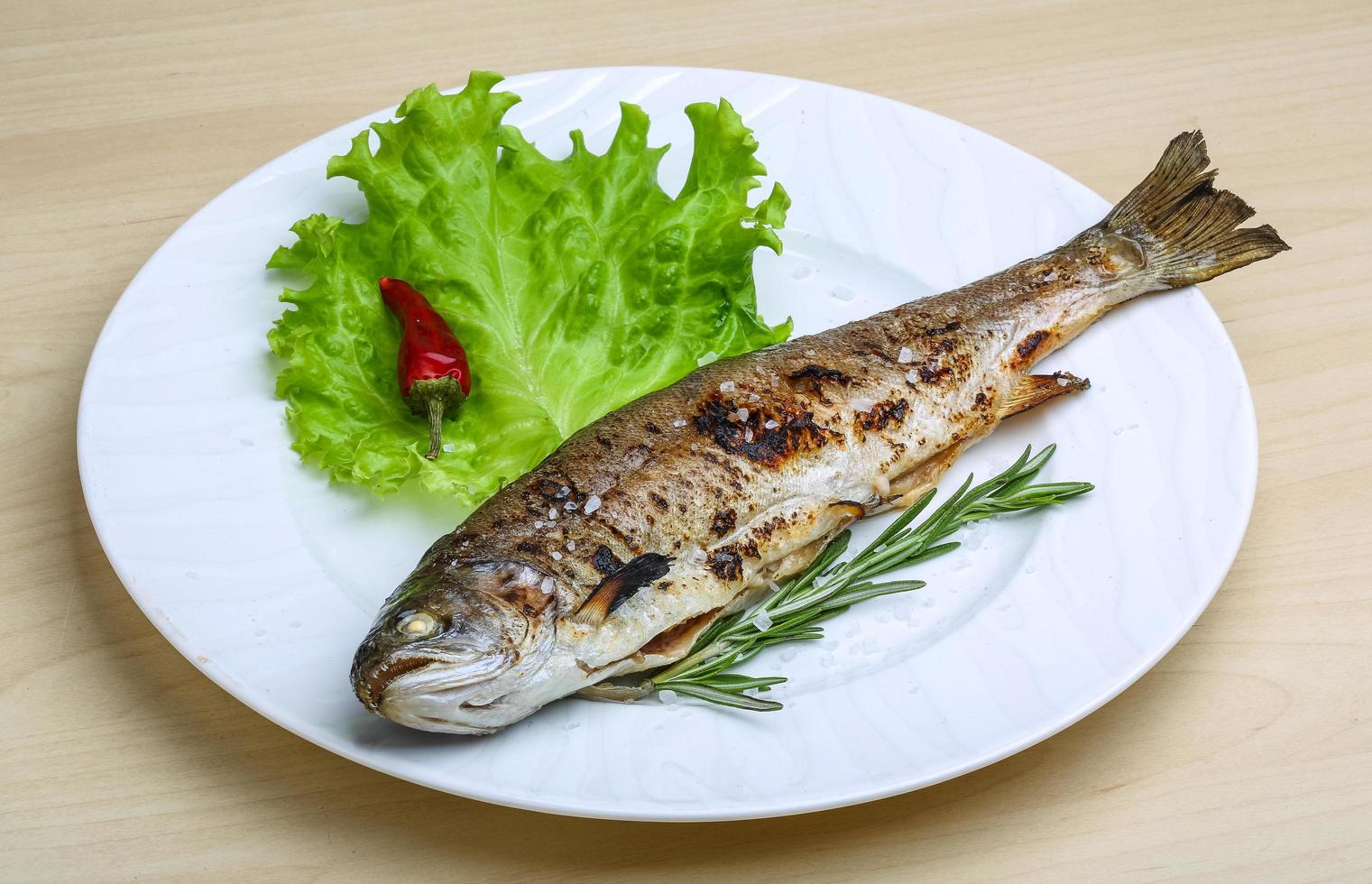 Grilled trout on the plate and wooden background photo